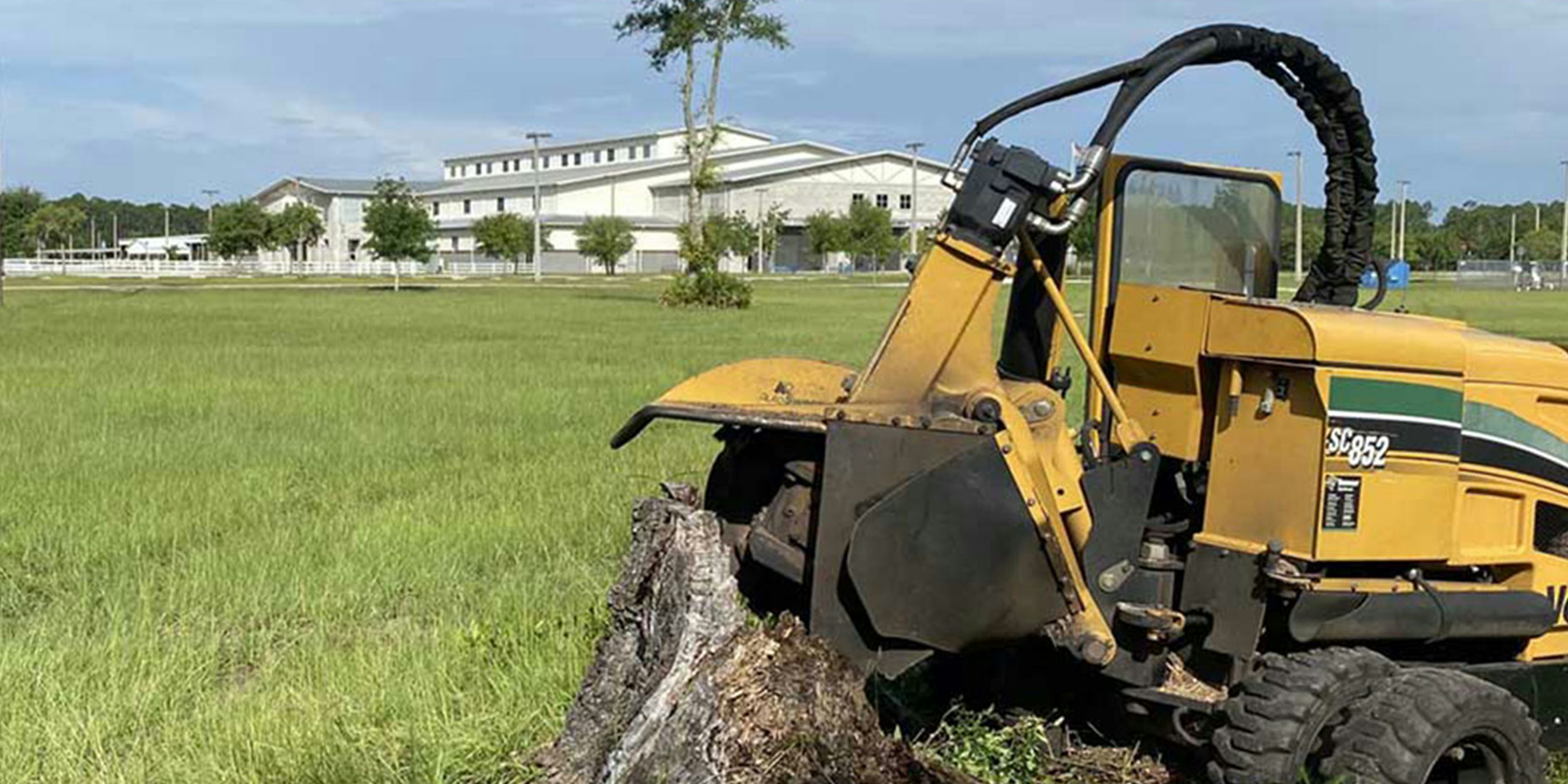 Stump grinder machine removing stump in open field